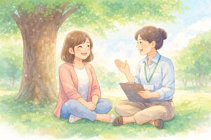 大きな木の下で、利用者と支援員が向かい合って座り、和やかに話をしている。